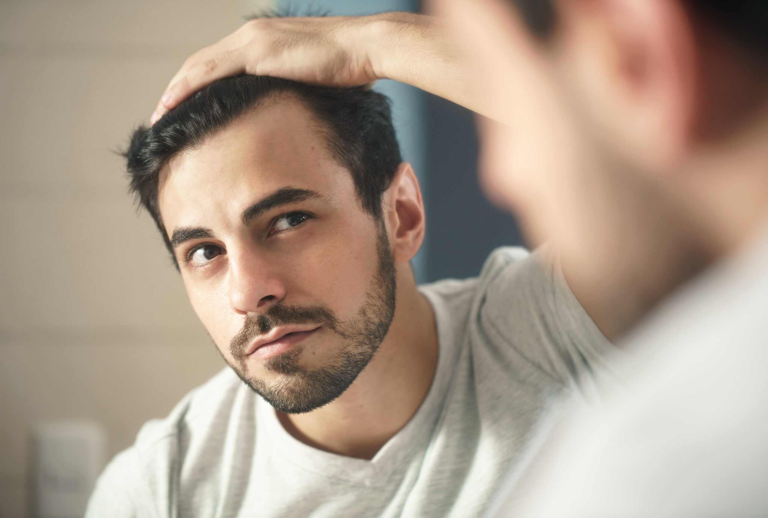 Homme qui se regarde dans le miroir soucieux de sas cheveux.